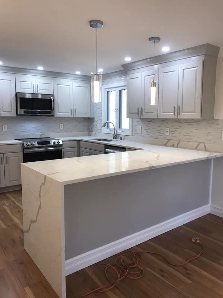 Remodeled kitchen with white cabinets and a quartz peninsula